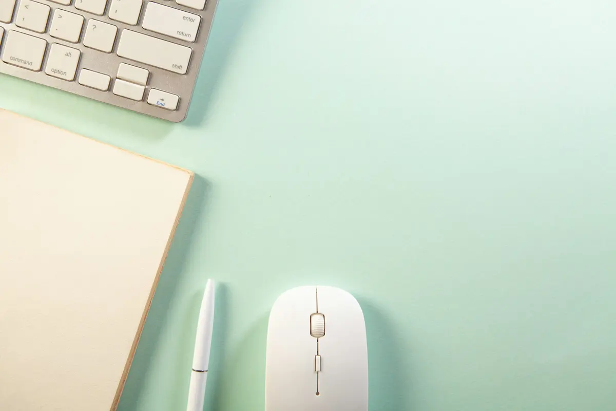 Keyboard, notebook, pen, and mouse arranged on a desk