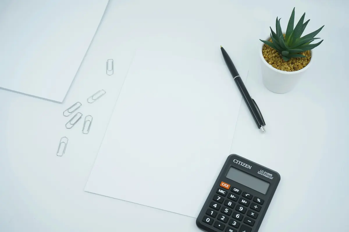 Calculator, pen, and blank paper on a desk